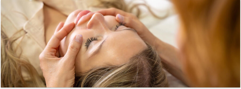 Mujer recibiendo un masaje facial antiestrés en un centro estético.